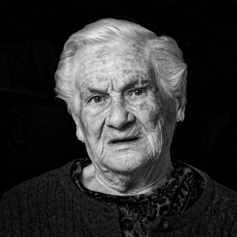 Señora mayor posa seria para un retrato fotográfico con fondo negro